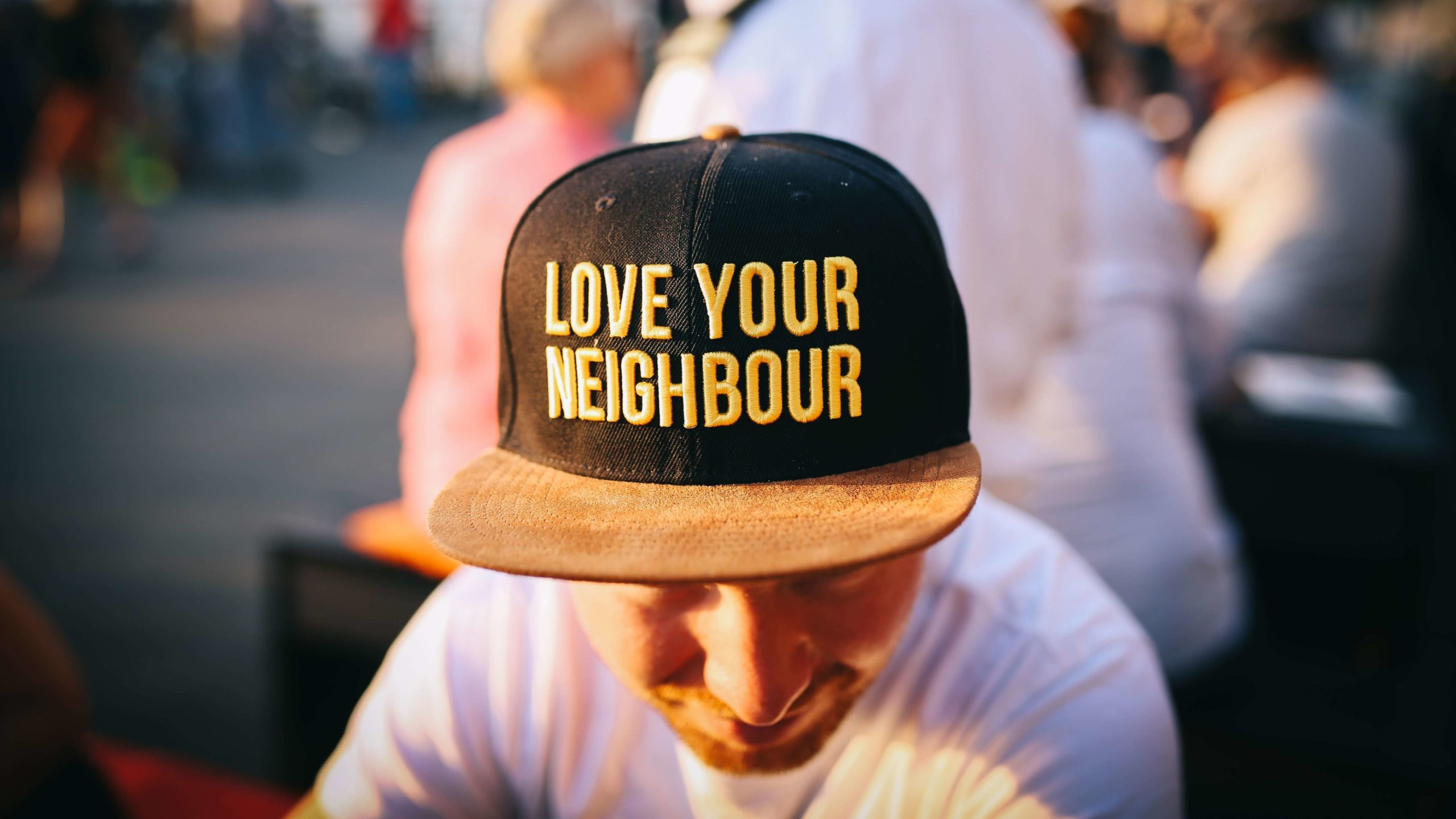 man in a cap that reads love your neighborhood, representing getting to know your geo farm in real estate